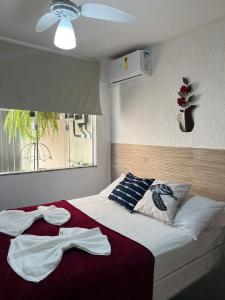 a bedroom with a bed with white sheets and a window at Pousada Casa Serra Alves in Búzios