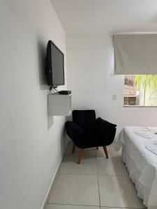 a room with a chair and a tv on a wall at Pousada Casa Serra Alves in Búzios