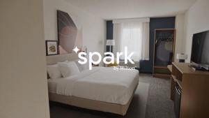 Un dormitorio con una cama blanca y un televisor. en Spark by Hilton Walker Grand Rapids North, en Grand Rapids