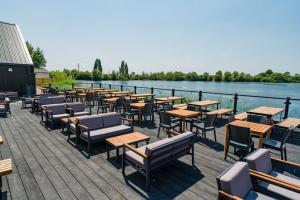 una fila de mesas y sillas junto a un cuerpo de agua en The Restful Rose at Chichester Lakeside, en Chichester