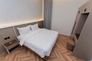 a bedroom with a white bed and a wooden floor at فندق نخبة العارض in Riyadh