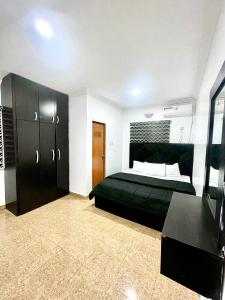 a bedroom with a black bed and a black cabinet at Dersym Apartment in Port Harcourt +7 photos