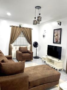 a living room with a couch and a television at Dersym Apartment in Port Harcourt