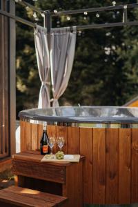 Un jacuzzi con dos copas de vino y una botella. en Honey House Wierchy- prywatna strefa SPA, en Jaszczurowa