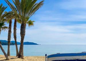 two palm trees and a bench on the beach at SELECT'soHOME - Appartement pour 4 personnes - Proche plage et parking privé -PARCFO11 in Le Lavandou +2 photos