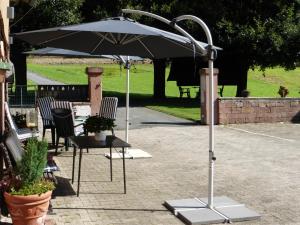 an umbrella in a patio with chairs and a table at Ferienunterkünfte Zur Mühle in Mossautal