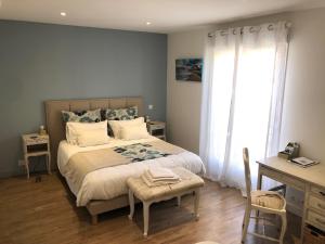 a bedroom with a bed with a desk and a window at Les chambres d'hôtes de Pascale in Mios