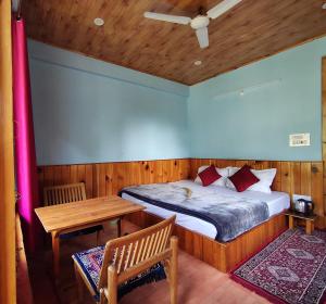 a bed in a room with a table and a bed gmaxwell gmaxwell gmaxwell at Mountain retreat in Jibhi