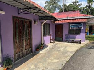 una casa morada con una puerta y una silla en ANA Homestay, en Hulu Langat