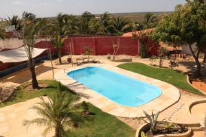 a large swimming pool in a yard with palm trees at Pousada Casa do Jardim in Canoa Quebrada