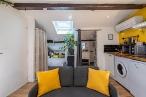 a living room with a gray couch and yellow pillows at Le Sunny - Cocon Lumineux, Climatisé, au Cœur de Castres in Castres