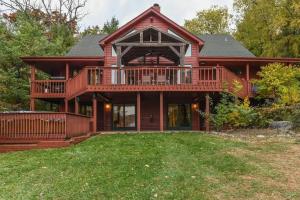 una grande casa in legno con un ampio ponte di Monthly or Seasonal Large Petite Lake 44 Lakehouse Retreat with Private Pier and Hot Tub secluded Deep in the Woods a Fox Lake