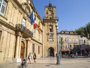 a building with a clock tower and people walking on a street at Le petit cardeur in Aix-en-Provence