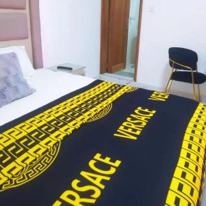 a bed with a yellow and black blanket on it at Chambre SCAT urbam in Dakar