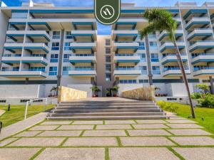 ein großes Apartmenthaus mit Palmen davor in der Unterkunft Brand New 1 BR Condo - Pool - Jacuzzi - Gym in Nuevo Nayarit