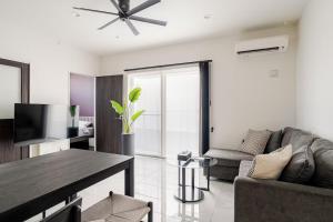 a living room with a couch and a television at Dual Life House Koza in Okinawa City