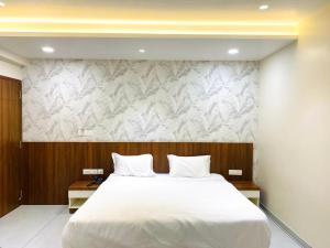een slaapkamer met een groot wit bed en een muur bij The Sapphire Hotel in Belgaum +176 foto's