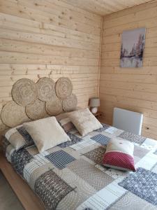 Un dormitorio con una cama grande con una pared de madera. en Gîte ambiance Chalet, en LʼEstrade