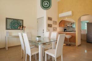une salle à manger avec une table en verre et des chaises blanches dans l'établissement 2BR Condo in Acapulco with Private Patio - Pool, à Acapulco