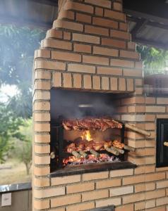 a brick oven with food cooking in it at Refúgio GRUPOS com piscina, churrasqueiras 38 min Águas Claras Brasília in Brasilia