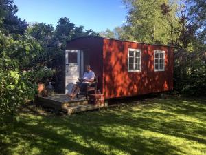 福堡Gipsywaggon的一名男子坐在小房子外面的椅子上