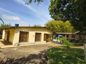 a small yellow house with a brick driveway at Chácara charmosa com piscina, campo de futebol in Guaratinguetá