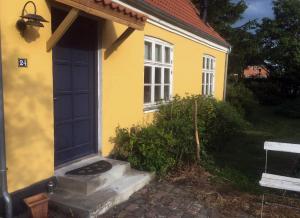 une maison jaune avec une porte bleue dans l'établissement Gipsywaggon, à Fåborg