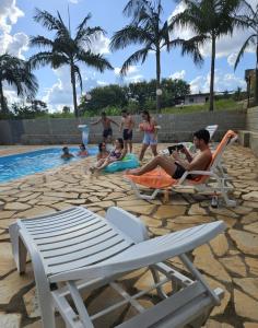 a group of people sitting around a swimming pool at Refúgio GRUPOS com piscina, churrasqueiras 38 min Águas Claras Brasília in Brasilia