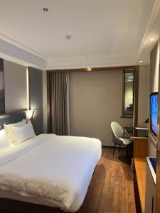 a hotel room with a white bed and a tv at Guangzhou CHILLNOW Hotel in Guangzhou