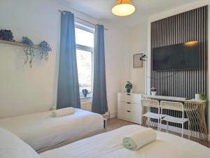 ein Schlafzimmer mit zwei Betten und einem Schreibtisch und einem Fernseher in der Unterkunft Charming 3-bed Home Near Centre Free Parking in York + 7 Fotos
