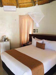 une chambre avec un grand lit blanc dans une pièce dans l'établissement Nkanga Hotel, à Kasane