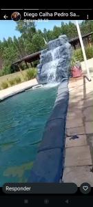 a swimming pool with a waterfall in the middle at Chácara Recanto Dona Celeida in Goiás