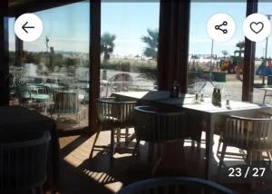 a restaurant with a table and chairs and a large window at A beautiful Beach House Gjiri Lalzit in Fushë-Draç