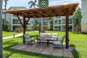un patio avec une table et des chaises sous une pergola dans l'établissement 2BR Condo in Acapulco with Private Patio - Pool, à Acapulco