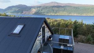 a house with a balcony with a view of a lake at The Loft at Log Ness in Inverness