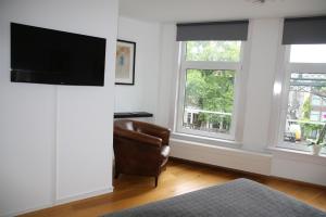 uma sala de estar com uma cadeira e 2 janelas em Bridge Inn em Amsterdã