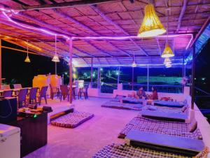 a room with purple lights and tables and chairs at Funky monkey Home stay in Hampi