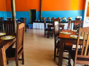 a dining room with wooden tables and chairs at Nkanga Hotel in Kasane