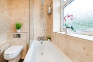 a bathroom with a tub and a toilet and a window at Bright & Lovely Apartment in Chelmsford in Chelmsford +37 photos