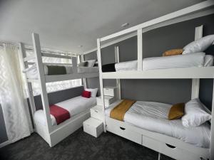 a room with three bunk beds and a window at M and B MotherCity Backpackers in Cape Town