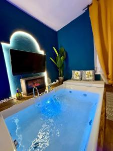 baño azul con bañera y TV en Ama Esclusive Spa Galliera, en San Vicenzo di Galliera
