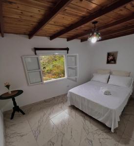 een slaapkamer met een bed, een tafel en een raam bij Cabaña jenny in Tovar