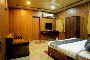 a bedroom with a bed and a chair and a television at Rio Royale in Bhimashankar