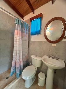 een badkamer met een toilet, een wastafel en een spiegel bij Cabaña jenny in Tovar