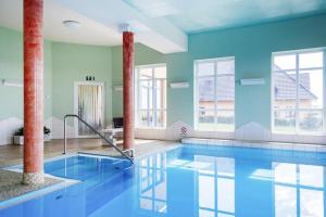 a large swimming pool with blue walls and windows at Holiday home in Markkleeberg near a lake in Markkleeberg