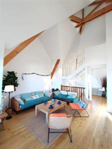 een woonkamer met een blauwe bank en een tafel bij Villa Bellevue - Anglo-Norman seafront house in Ouistreham