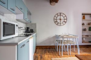 a kitchen with a table and a clock on the wall at Le nid des rois - Terrasse en hyper centre in Blois