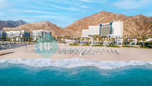 an aerial view of a beach with chairs and buildings at Beach Resort Address Luxury 2BR with Maid Sea View in Fujairah