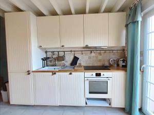 a kitchen with white cabinets and a stove top oven at Cosy Villa by sea ! - two terraces in Ouistreham