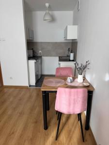 a dining room table with two pink chairs and a kitchen at Stare Miasto 10 in Malbork